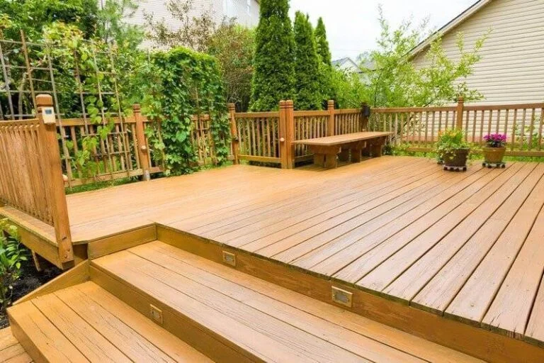 A large deck with mulltiple steps  and railing stained light brown