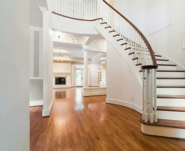 Beautiful home featuring a majestic staircase with wood-finished handrails and banisters, complemented by off-white walls.