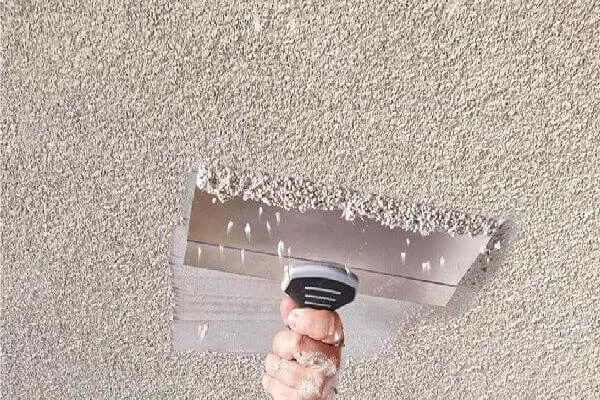 Professional tech scraping old ceiling textute ( popcorn style) using a wide scraper